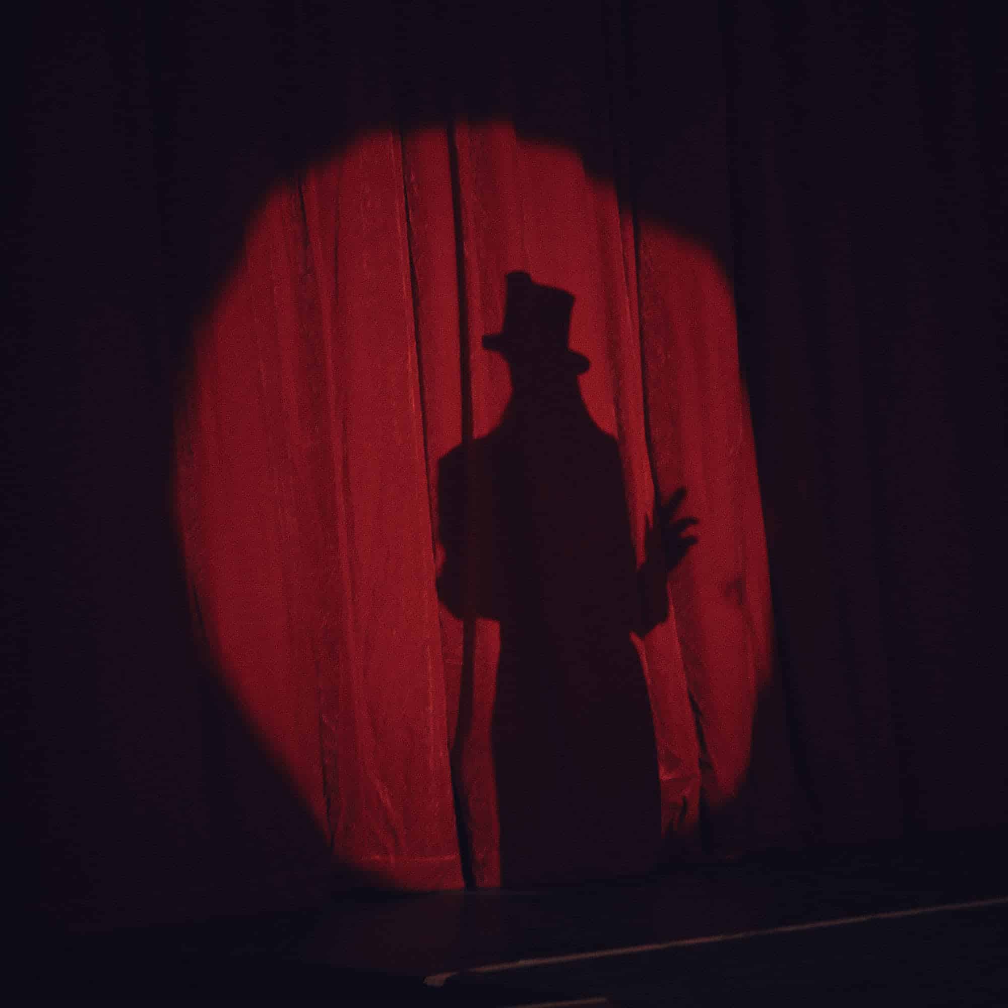 Kreisrunder Lichtspot auf dem roten Vorhang im Zirkus mit der silhouette von Julica.